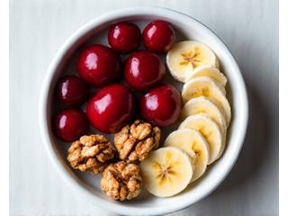 Plato de comida saludable con cerezas, nueces y plátano, ingredientes conocidos por promover el sueño.